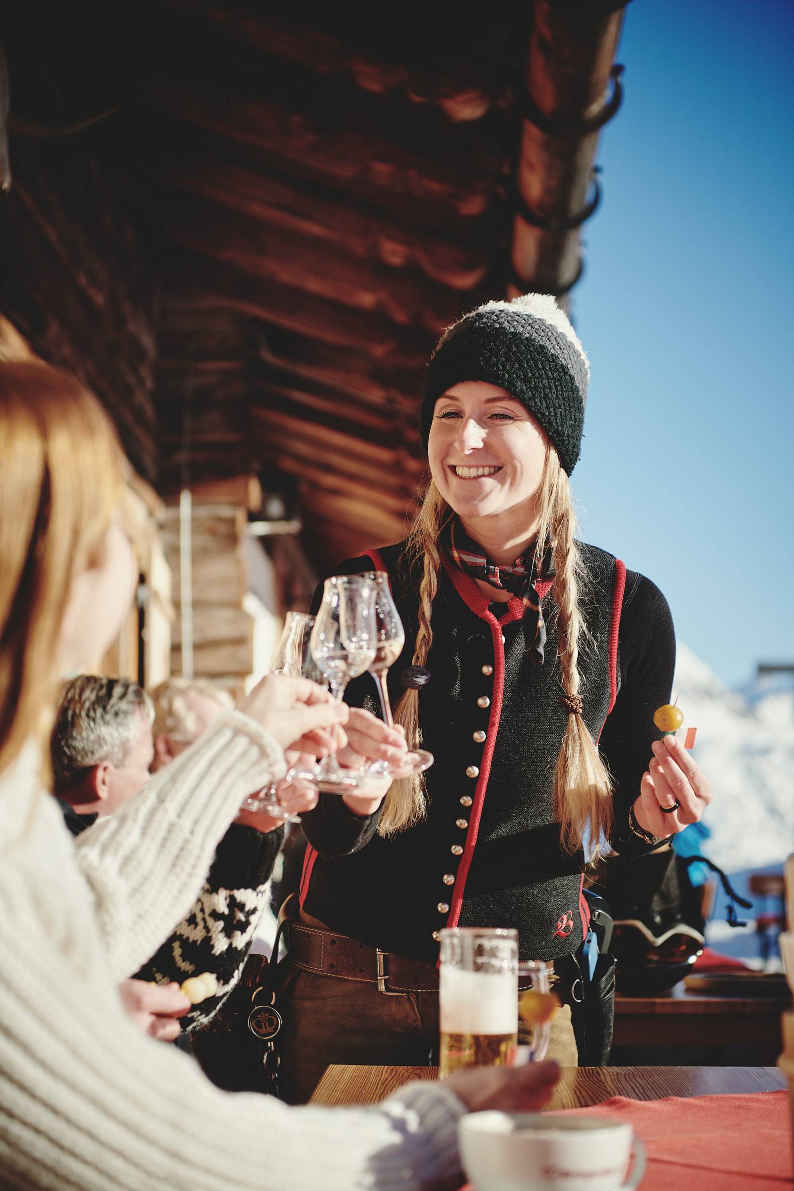 Frau hält eingelegte Mirabelle und Schnaps in der Hand vor einer rustikalen Berghütte