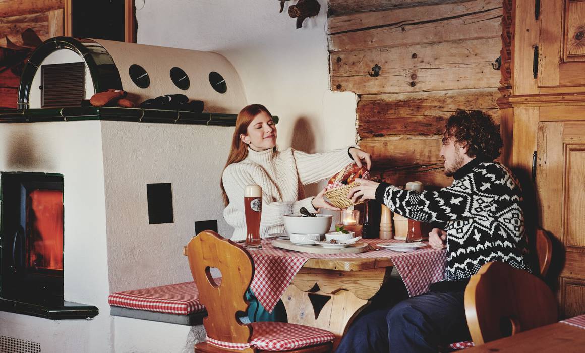 Mann und Frau essen in rustikaler Berghütte neben dem Kamin