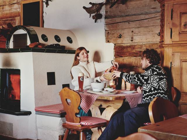 Mann und Frau essen in rustikaler Berghütte neben dem Kamin